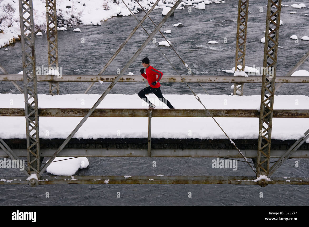 A man running across a tressel bridge on a snowy day near Truckee in California Stock Photo