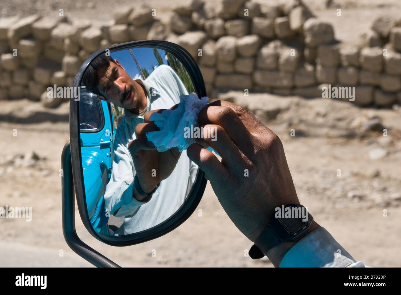 A portrait of a Pakistani man cleaning the mirror of his jeep Stock Photo