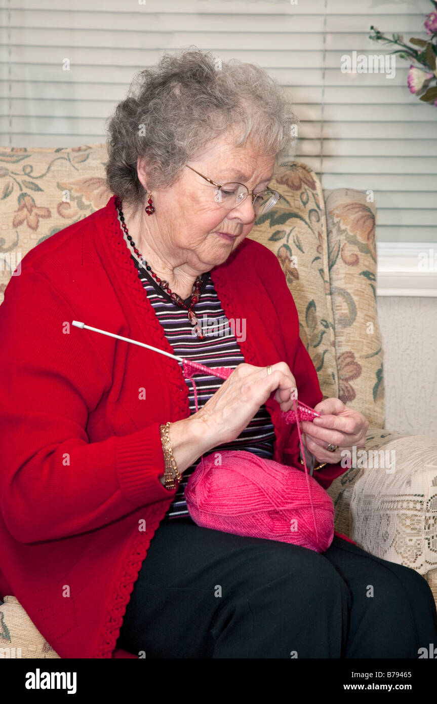 Elderly lady sat in armchair, knitting. Stock Photo