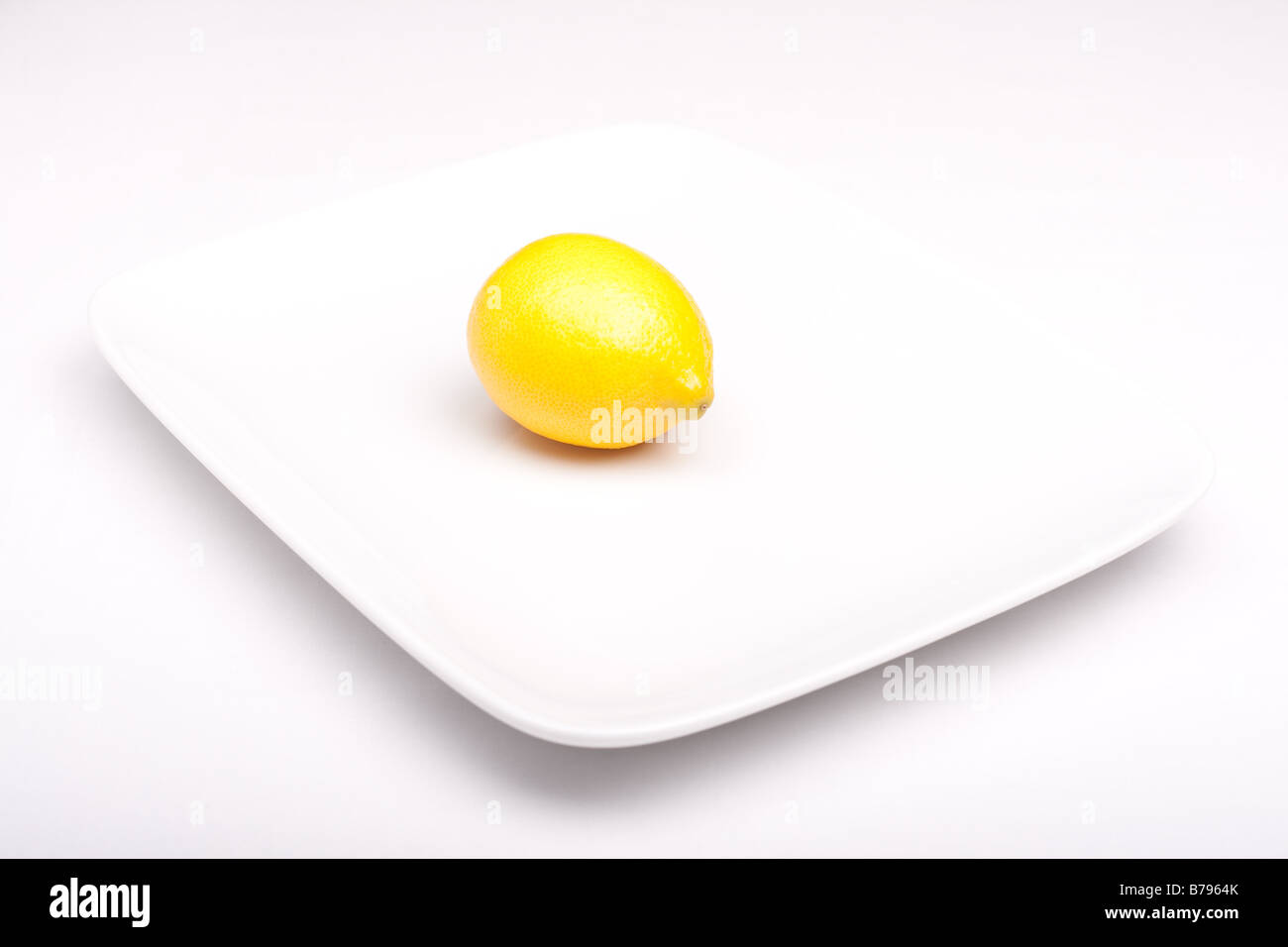 Single lemon on white plate Stock Photo