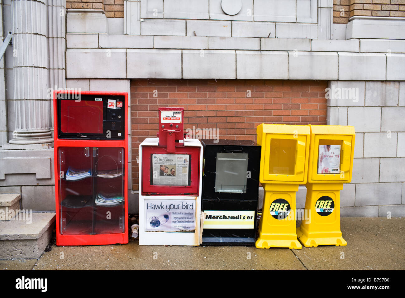 A row of newspaper dispensers on a side walk Stock Photo