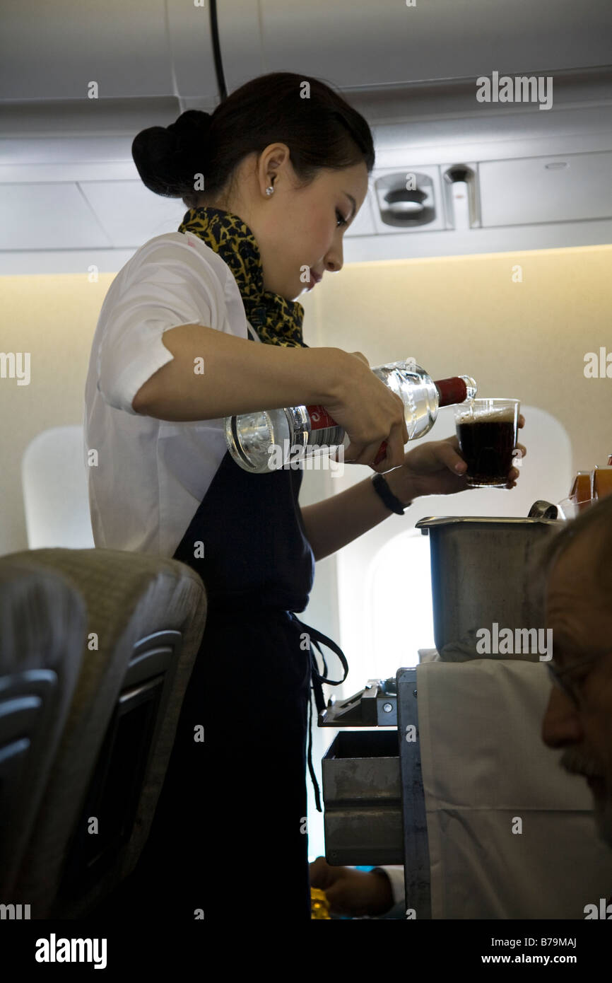 Cabin Crew Air Stewardess With A Trolley Cart Pours Spirit