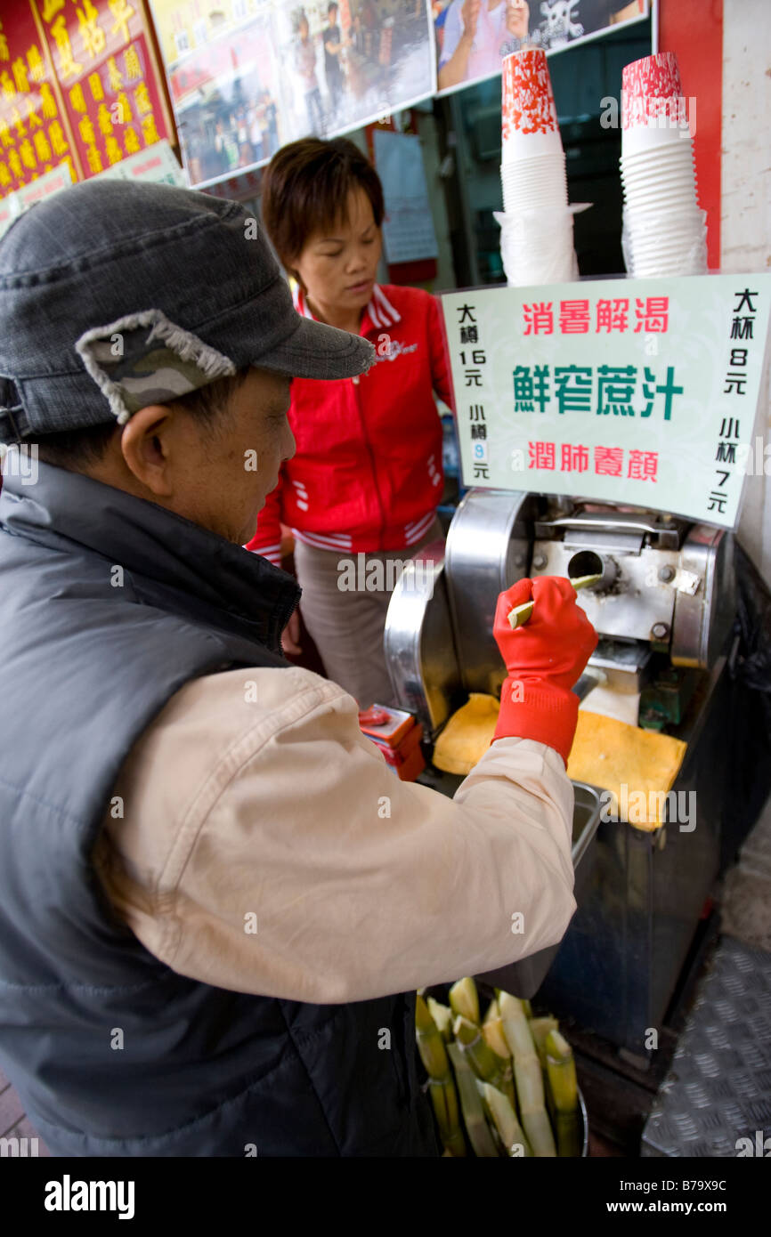 A vendor making cane juice by grinding up sugar cane in Hong Kong Stock