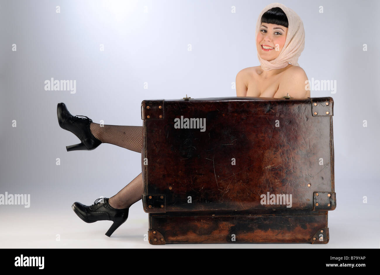 Funny image of a beautiful woman hide inside a leather suitcase Stock Photo