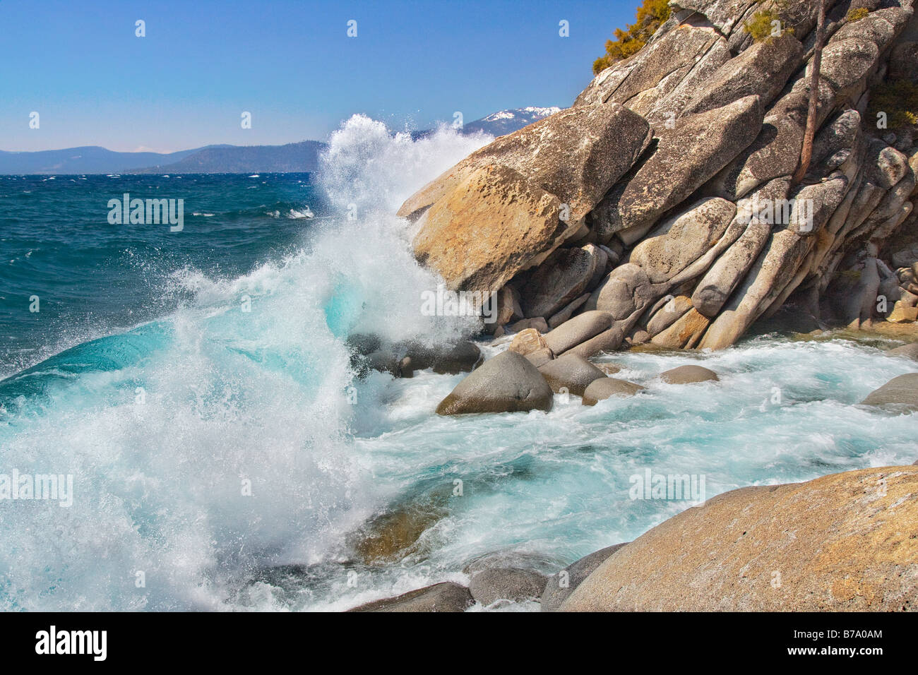 A rocky shoreline and breaking waves on the east shore of Lake Tahoe on a windy day in the spring Stock Photo