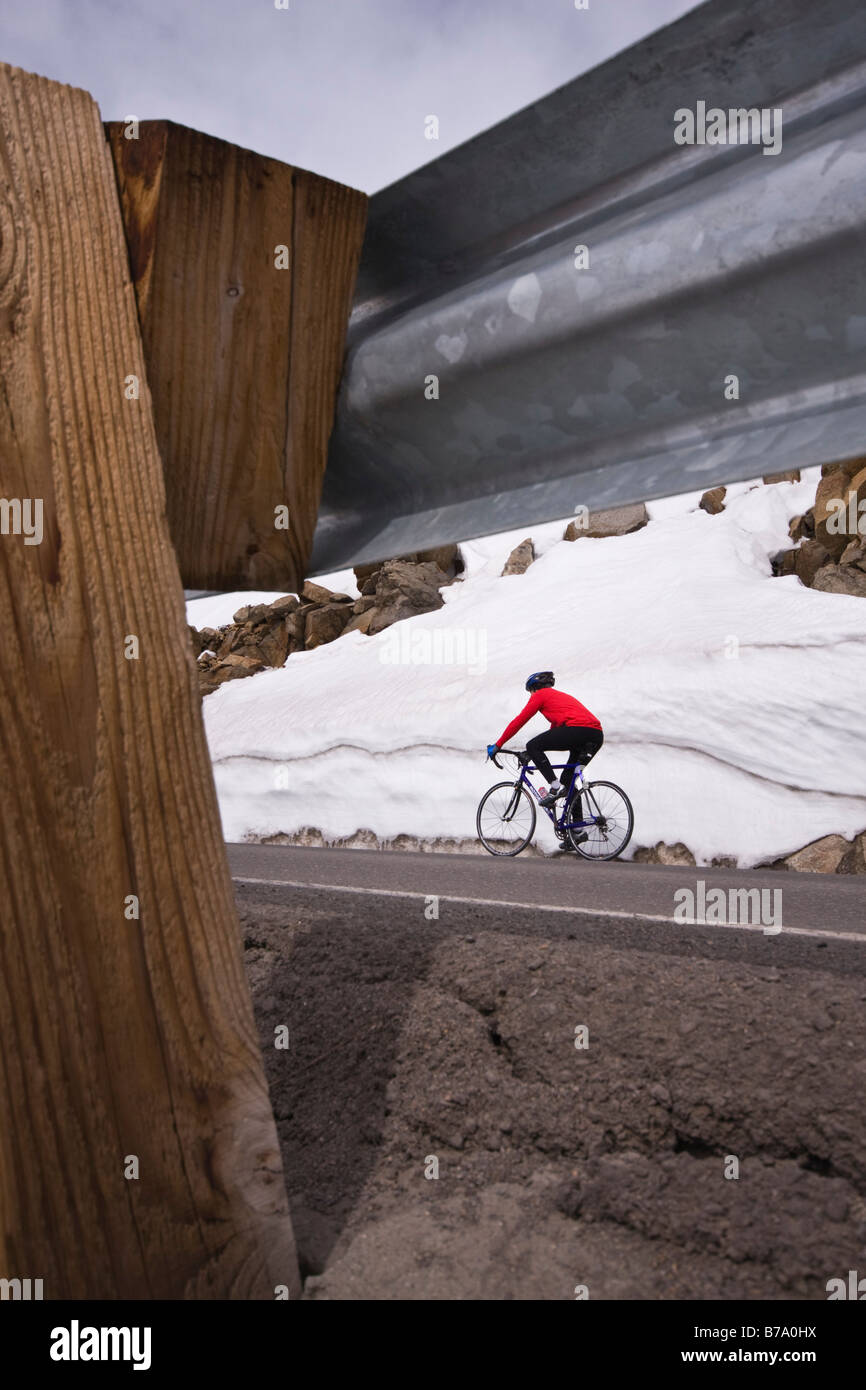 A man climbing uphill on a bicycle in winter on Donner Summit in California Stock Photo