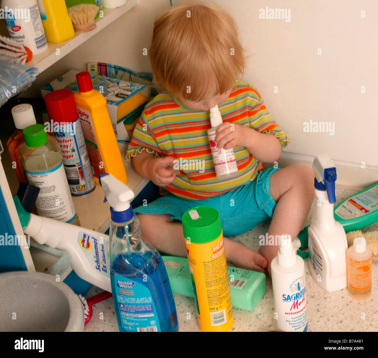 Toddler playing with cleaning agents Stock Photo