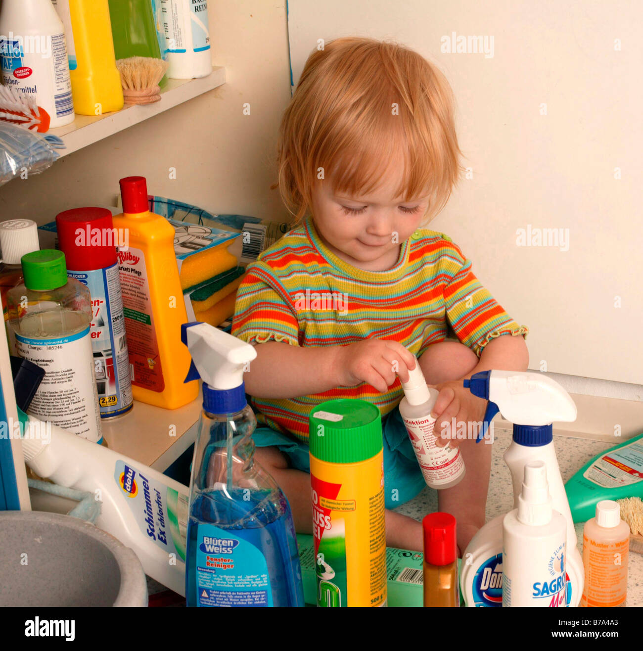 Toddler playing with cleaning agents Stock Photo