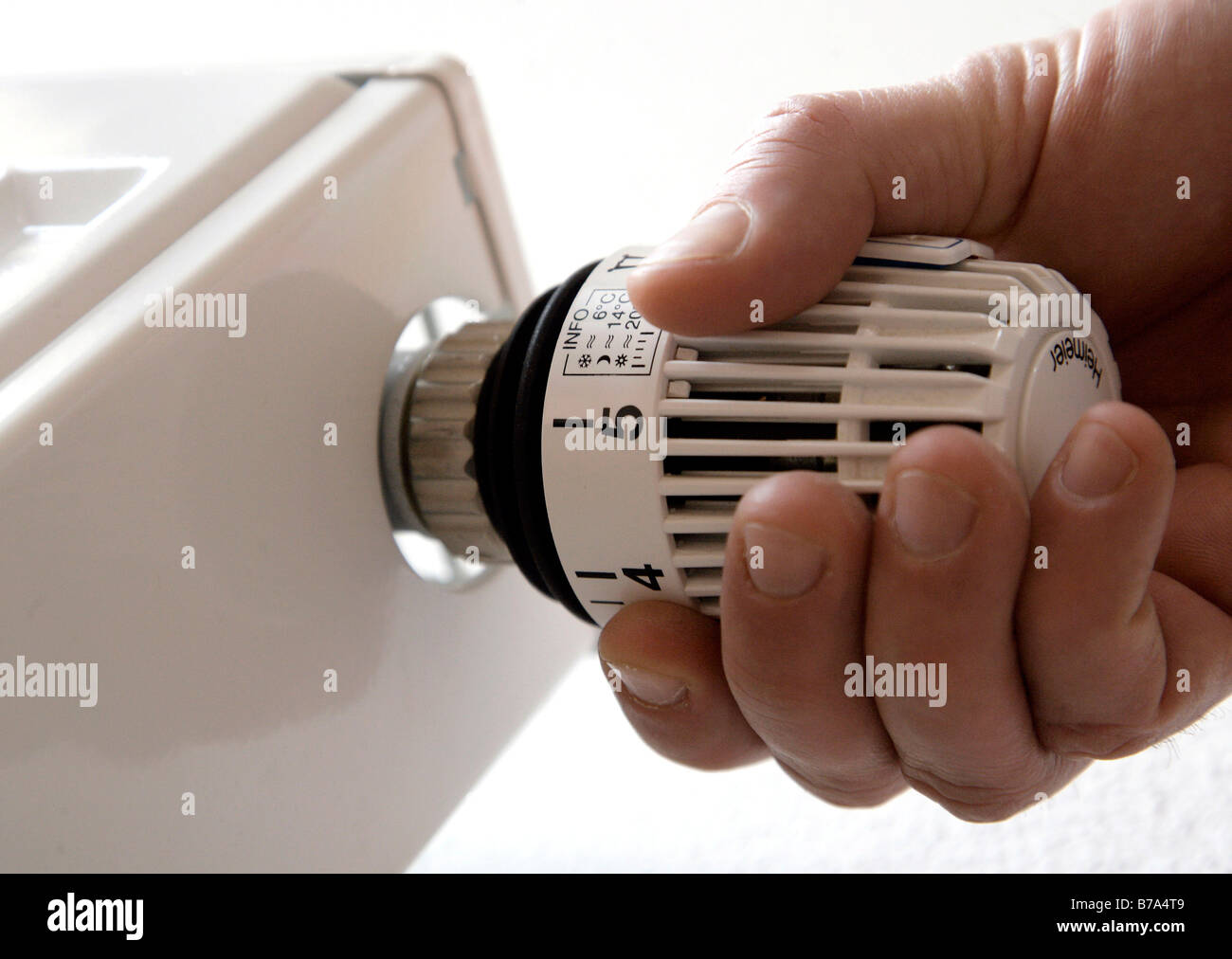 Hand turning a heating thermostat, Germany, Europe Stock Photo