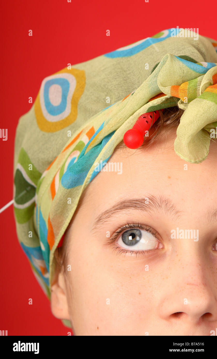 Teenage girl wearing hair curlers and head scarf looking dressed up to look like an old fashioned house wife Stock Photo