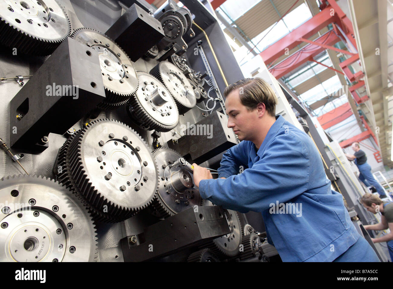 Laborer tightening the gears of an impression cylinder of a reel-fed offset printing machine, manufacture, Production MAN Rolan Stock Photo