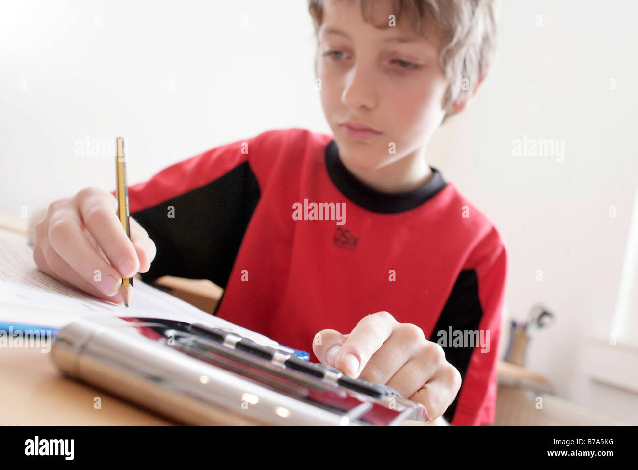 Young 10 year old boy doing his homework with a calculator Stock Photo