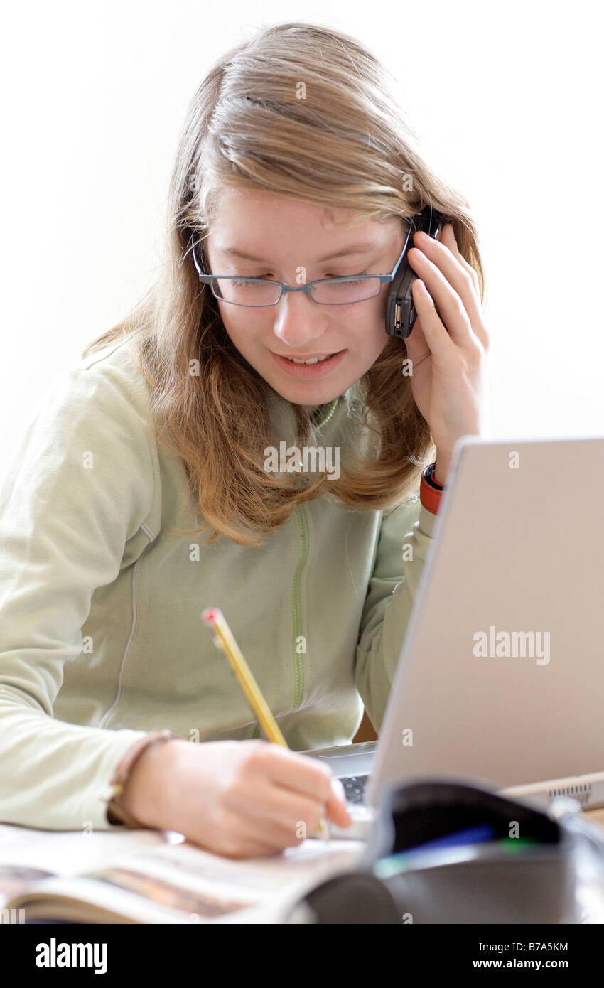 Young 13 year old girl, teenager, on a laptop and cell phone simultaneously Stock Photo