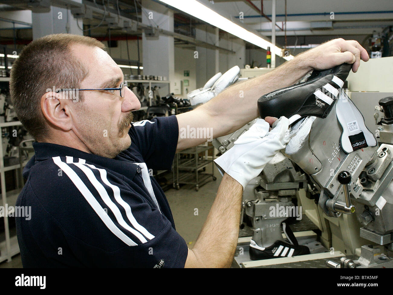 Worker pulling a shoe off the casting machine for adding the soles, production of Copa Mundial football boots in the Scheinfeld Stock Photo