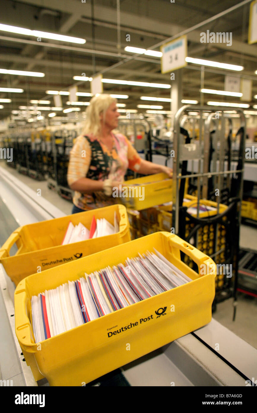 Employee of the Deutsche Post AG, German post, putting boxes of letters onto a roll container so they can be transported to the Stock Photo