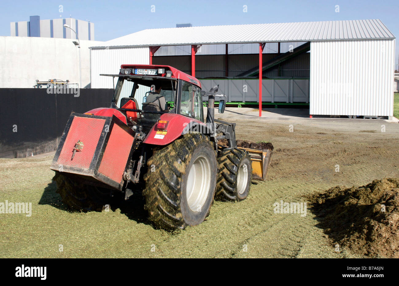 Front loader tractor spreading silage in front of the distribution compound for a biogas plant of the Schmack Biogas AG in Schw Stock Photo
