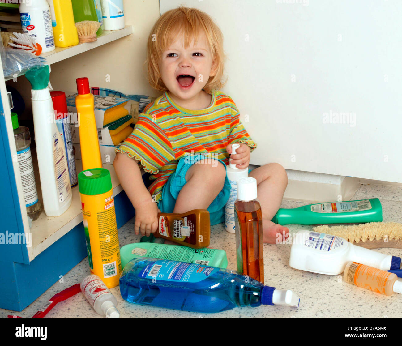 Toddler playing with cleaning agents Stock Photo