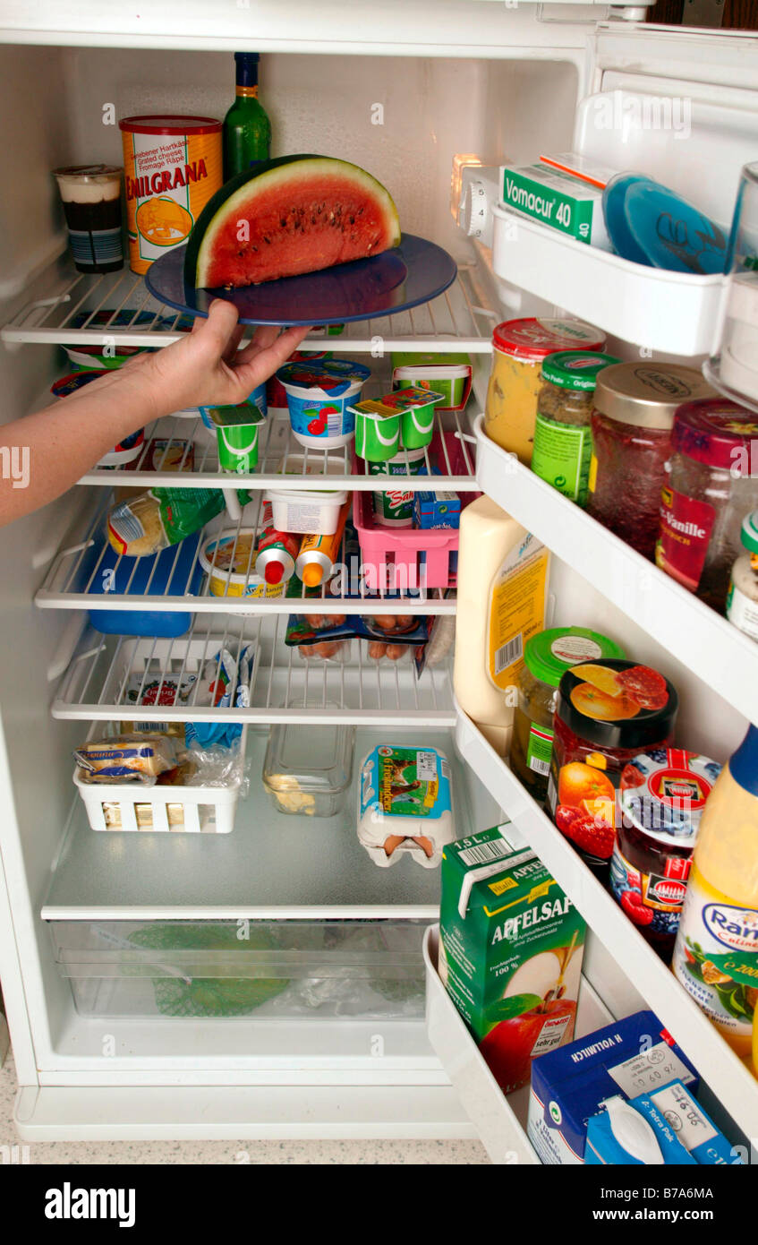 Woman putting food into the fridge, in the kitchen Stock Photo