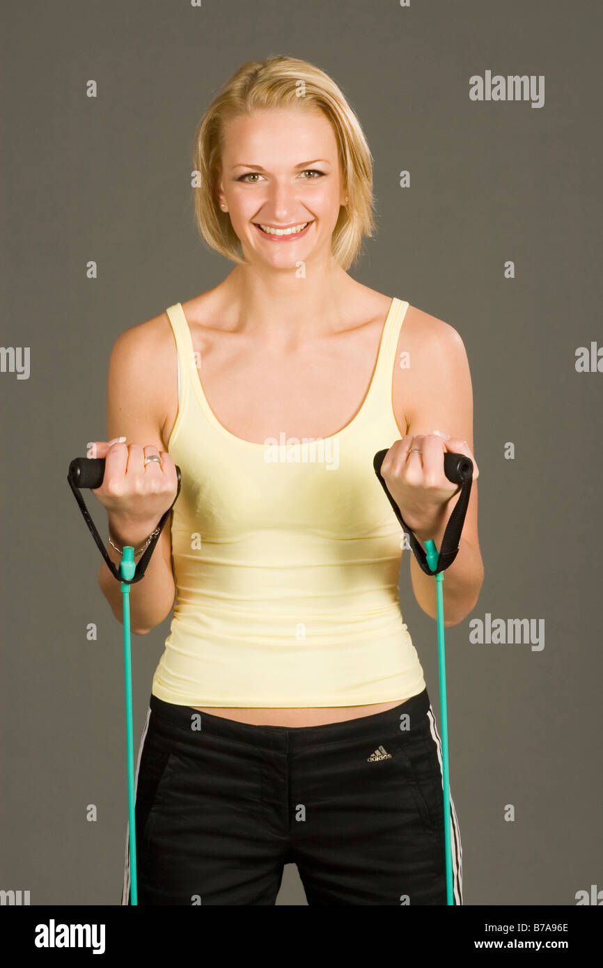 Young blonde woman wearing sportswear, using tubes for bodyforming and training her muscles Stock Photo