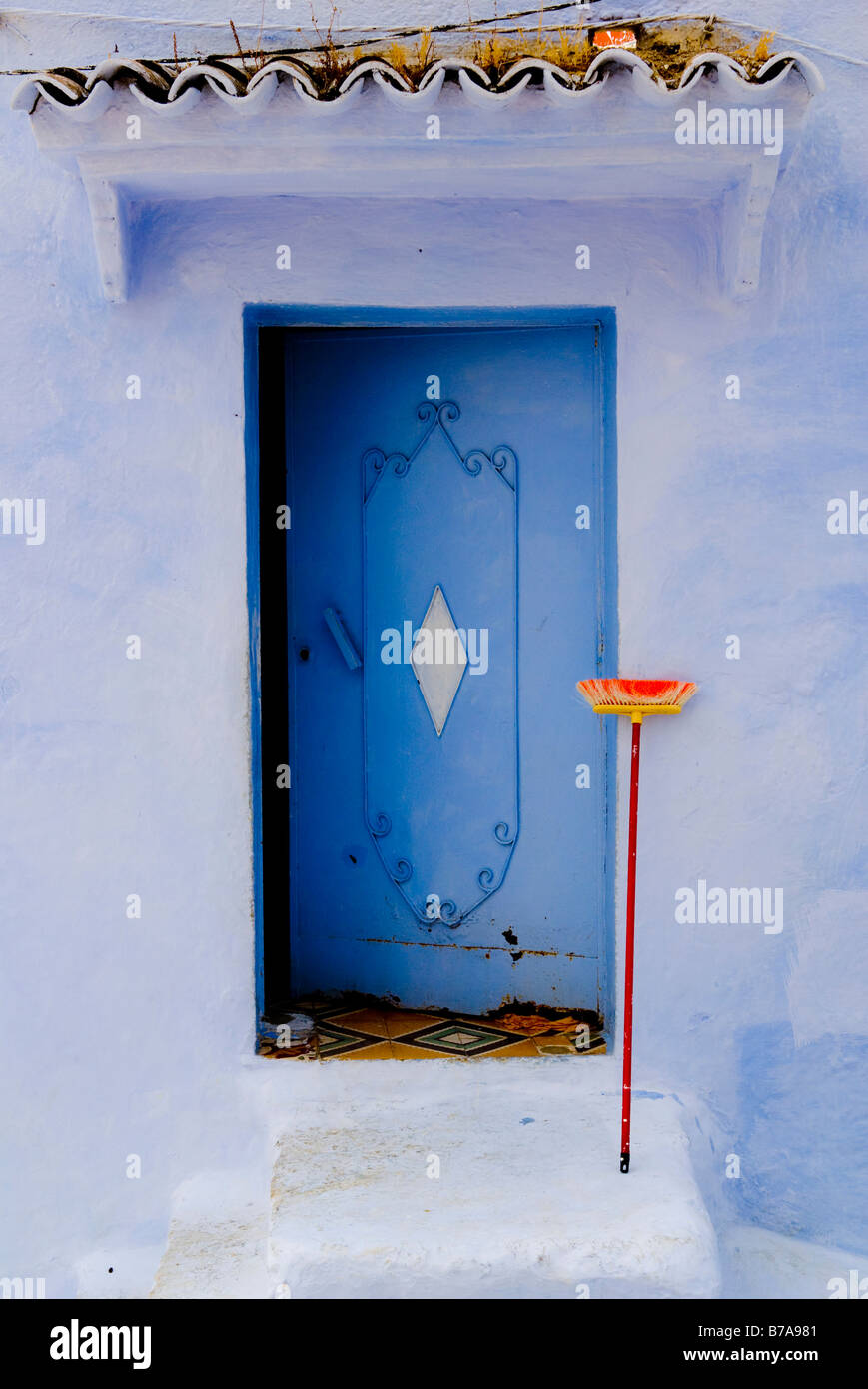 Open door with broom in front of residential house in Chefchaouen, Morocco, Africa Stock Photo