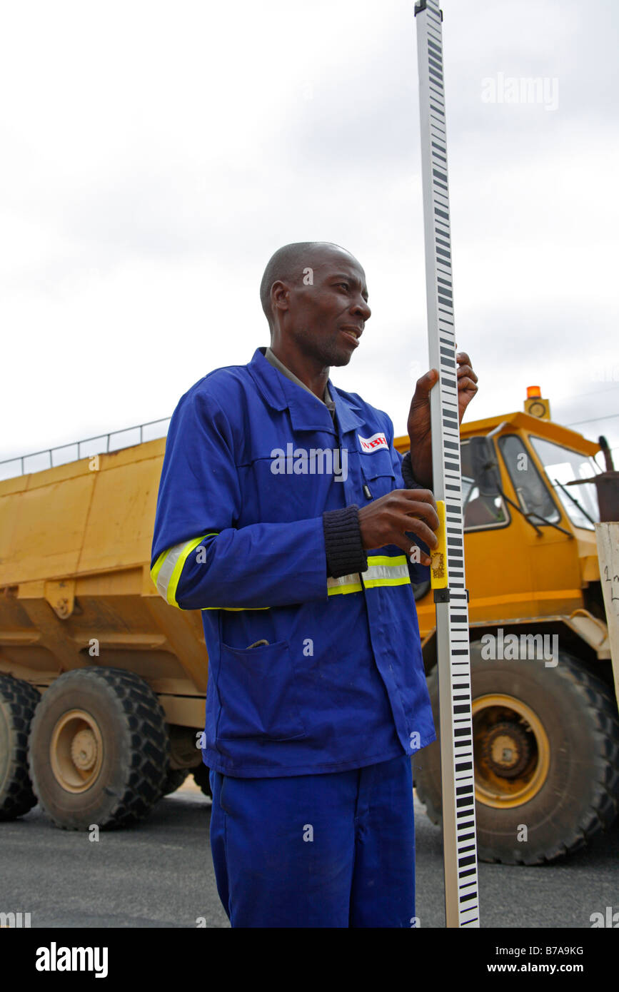 A surveyors assistant holding a staff during road construction survey