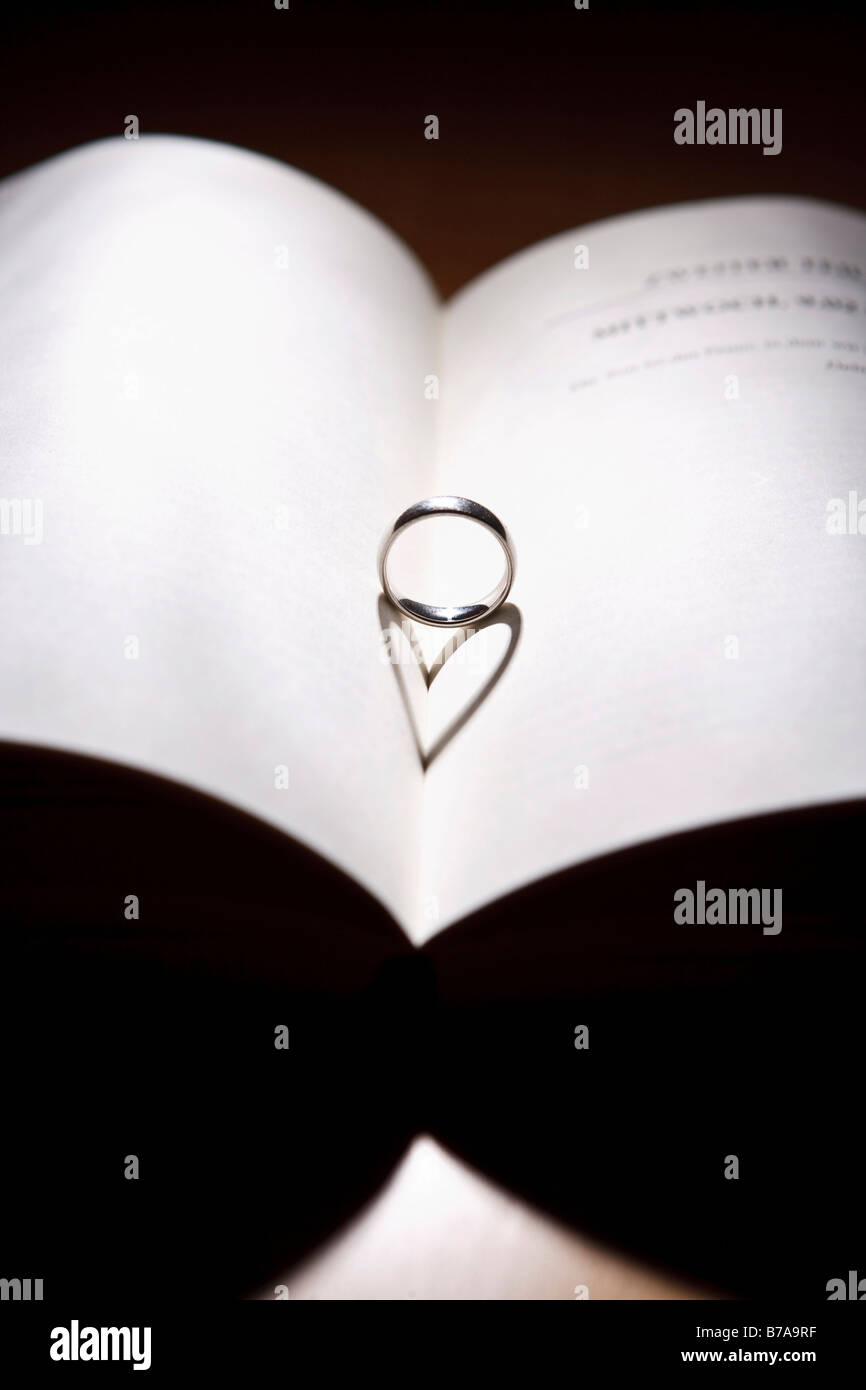 Ring with a heart-shaped shadow on an open book Stock Photo