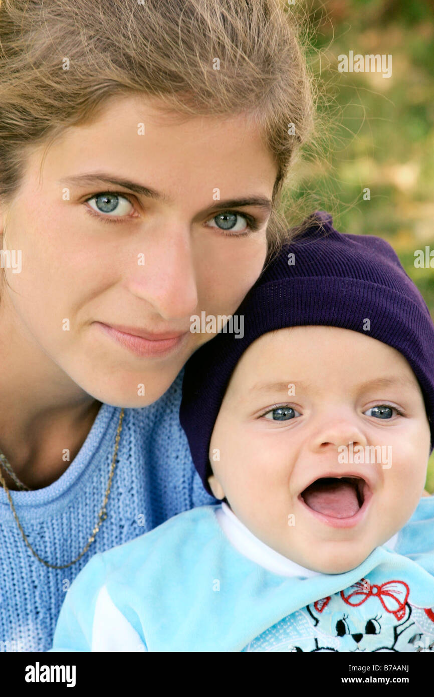 Baby boy wearing a blue cap, content, with mother Stock Photo