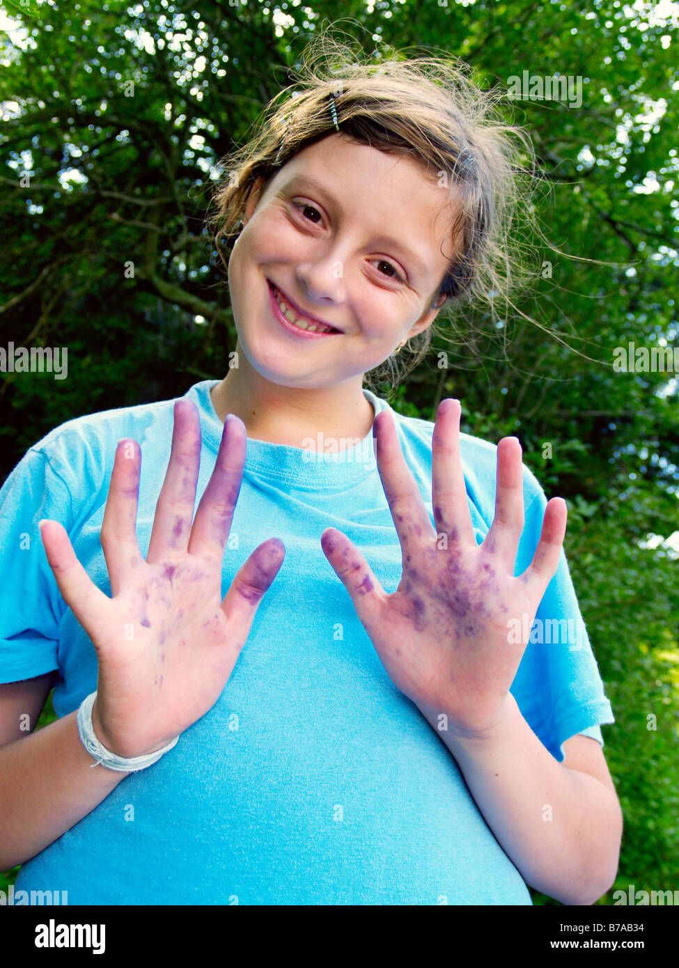 13 year old girl with blue colored hands from blueberries Stock Photo