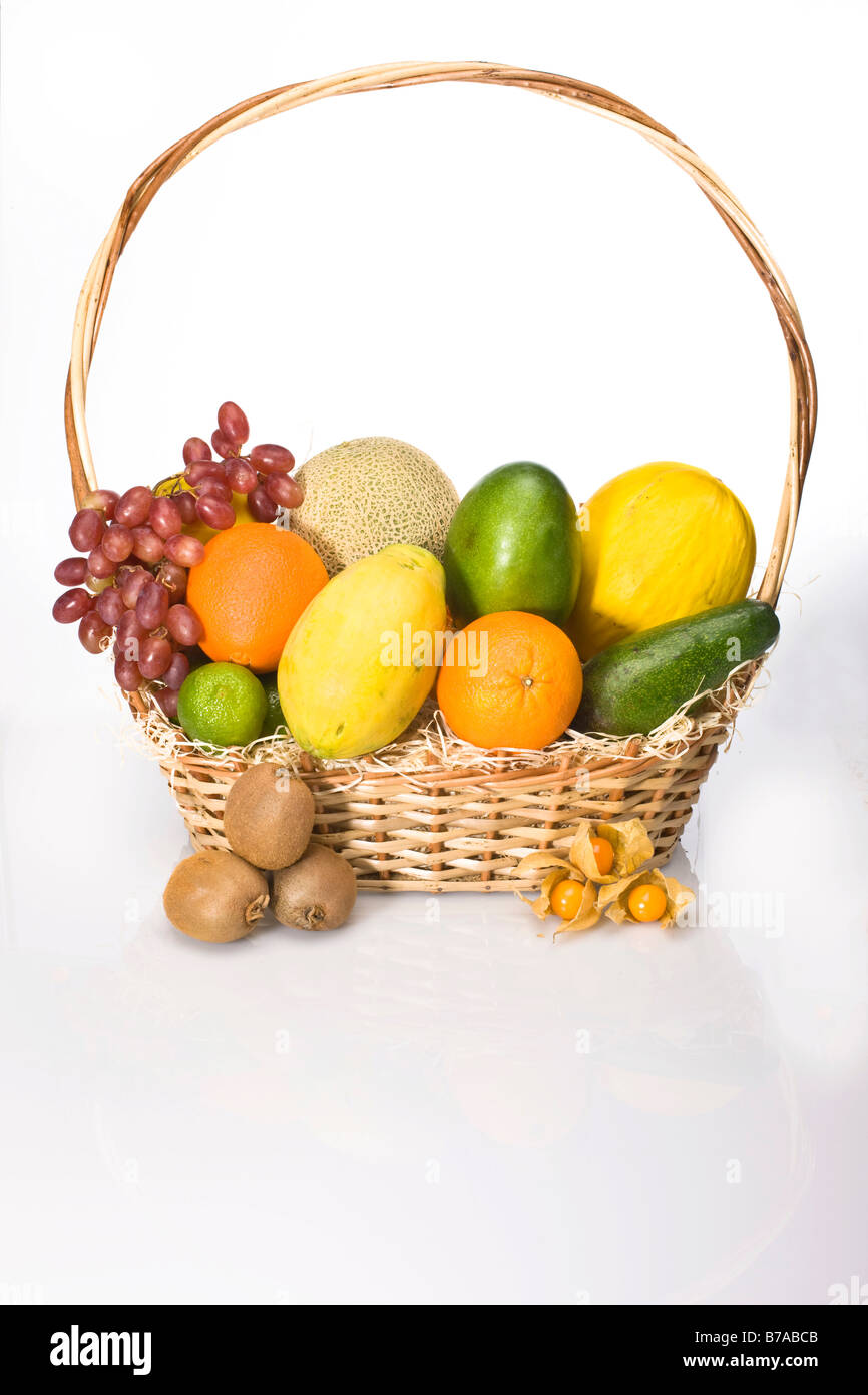 Exotic fruit in a basket, melons, grapes, oranges, lime, physalis, kiwis, mango, papaya, avocado Stock Photo