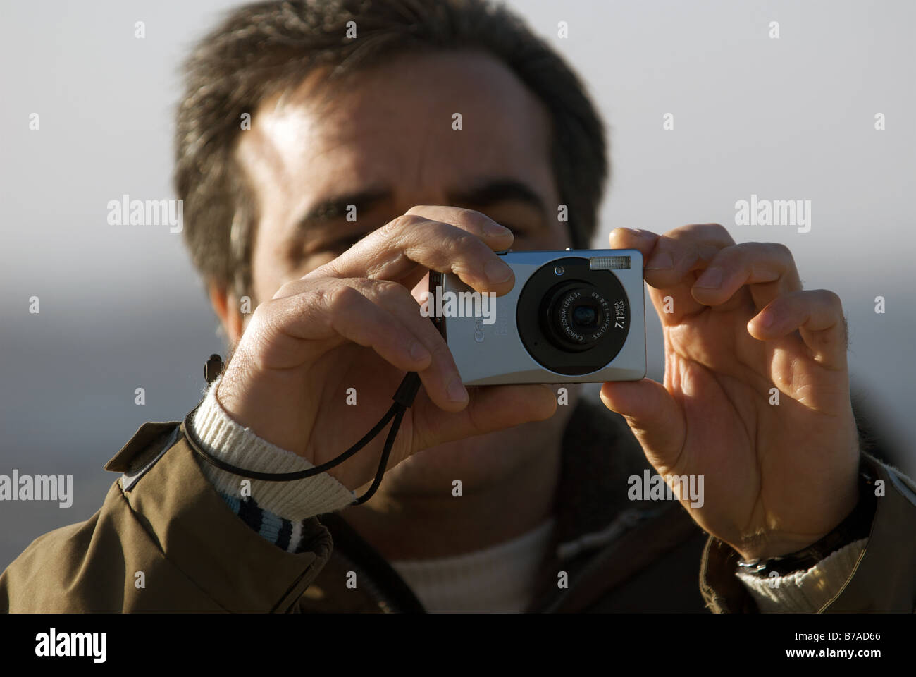 Man taking a picture using a Canon Ixus 75 digital camera. Stock Photo