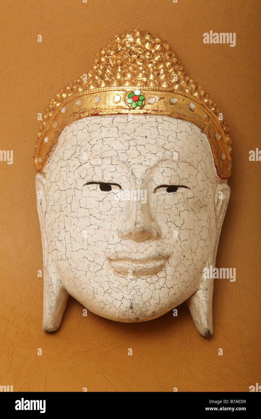 handcrafted wooden buddha face decorative mask on yellow background Stock Photo