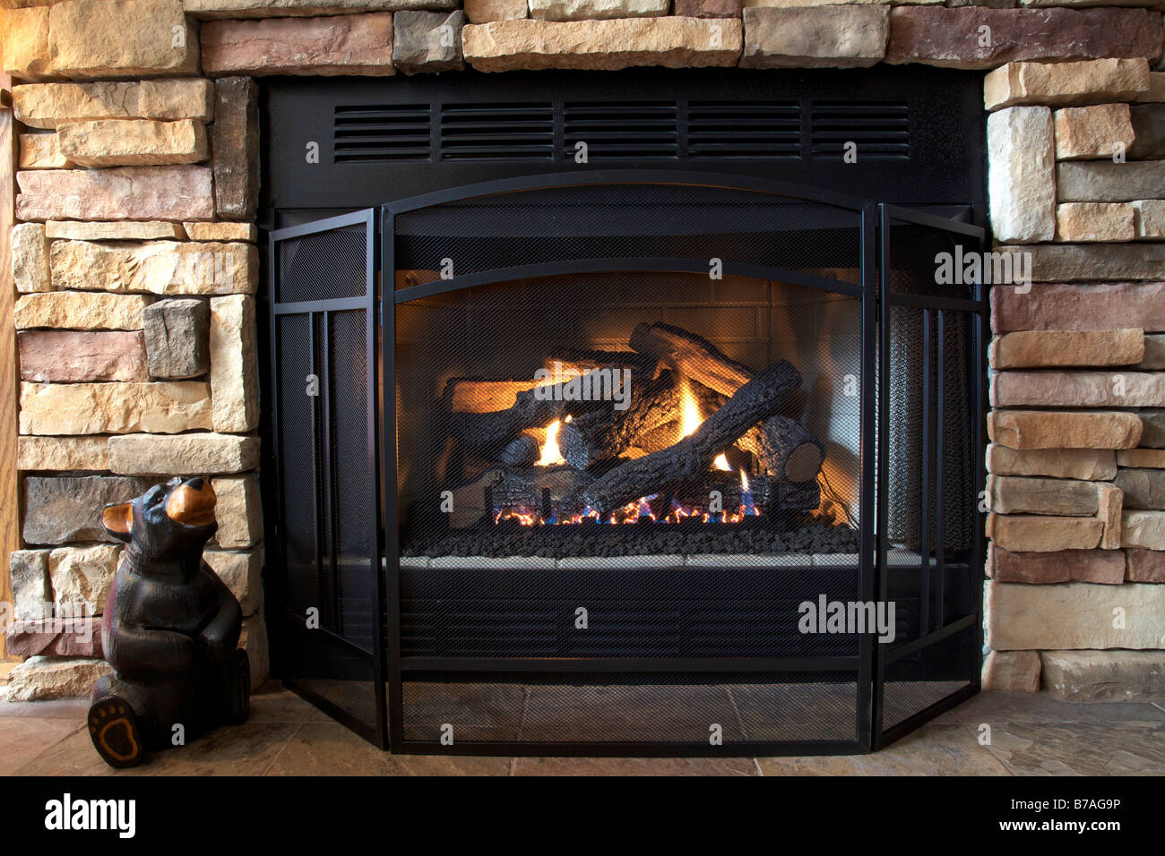 A gas log fireplace provides both emotional and physical warmth as the afternoon sun streams in on a cold winter day Stock Photo