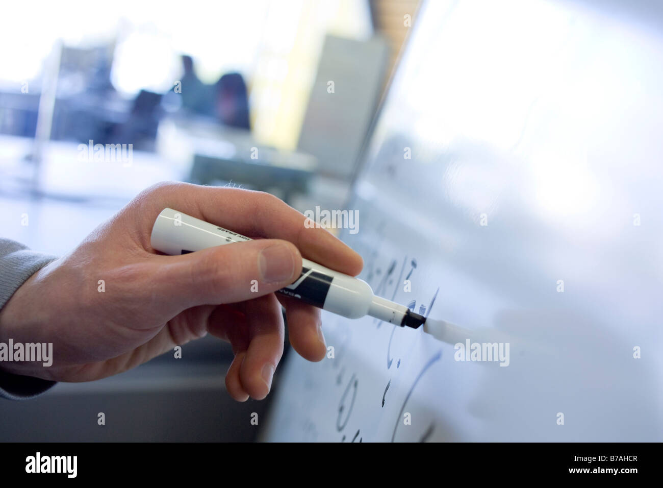 A man s hand writing mathematical equations on a whiteboard Stock Photo