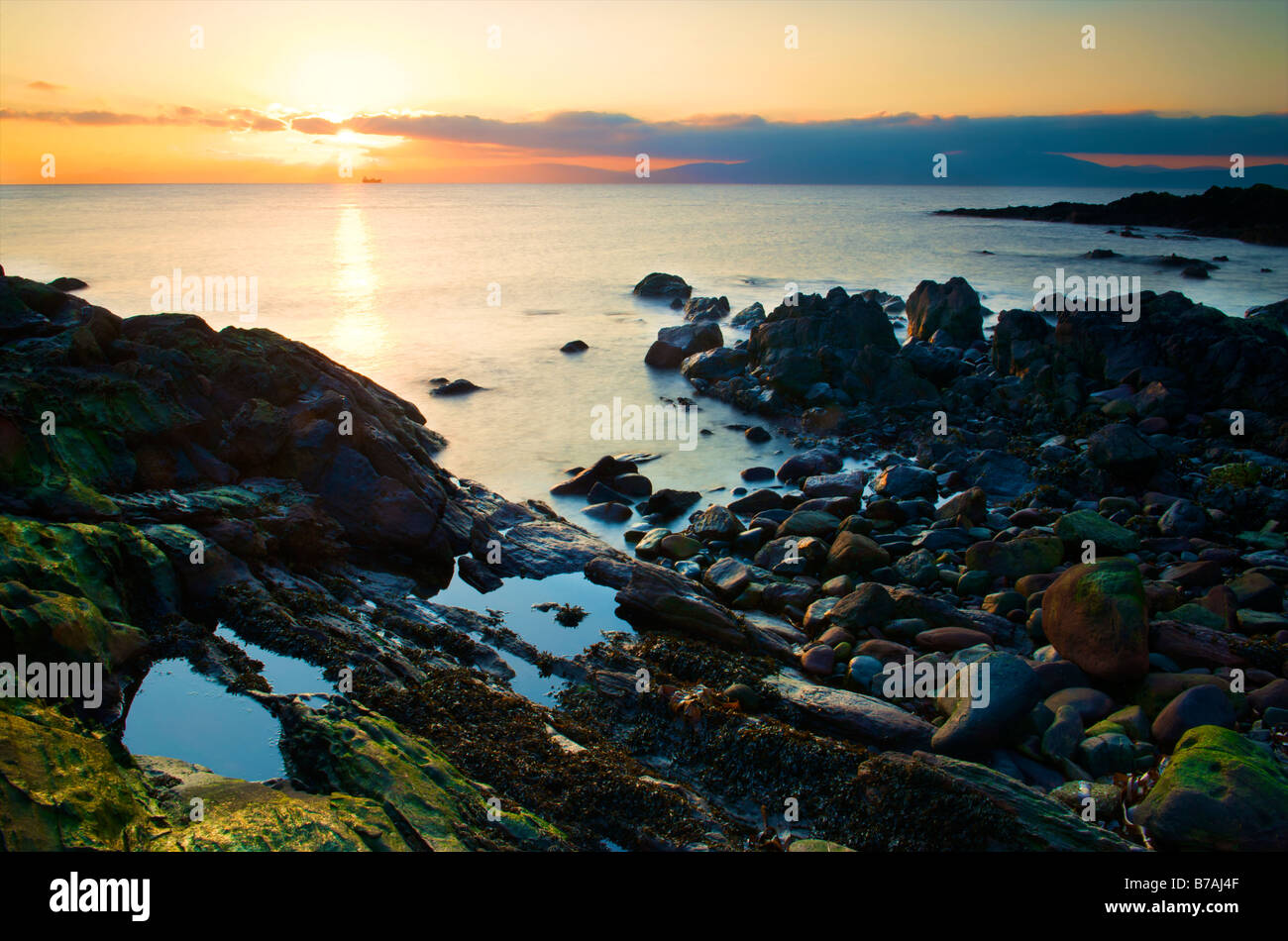 seascape view of the river clyde at sunset over a rocky outcrop at low tide Stock Photo