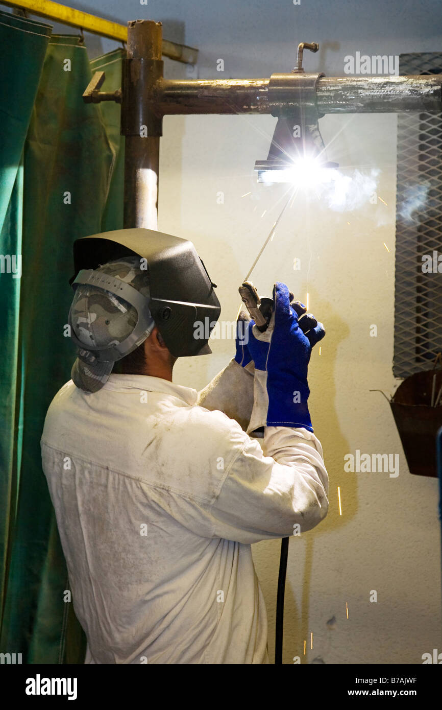 Welder in a metal shop welding overhead Actual welder working according