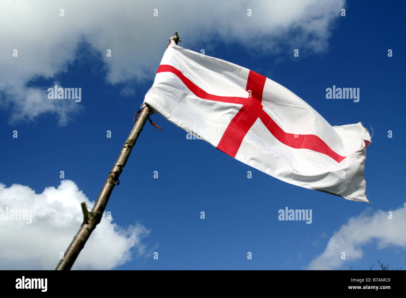 England's St George flag on wooden pole, with blue sky background Stock Photo