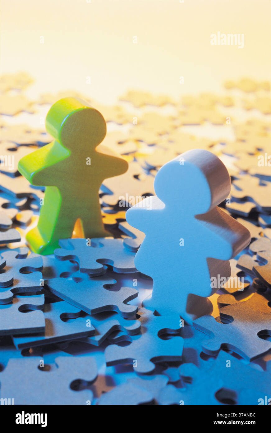 Wooden children figures on pieces of jigsaw puzzle Stock Photo