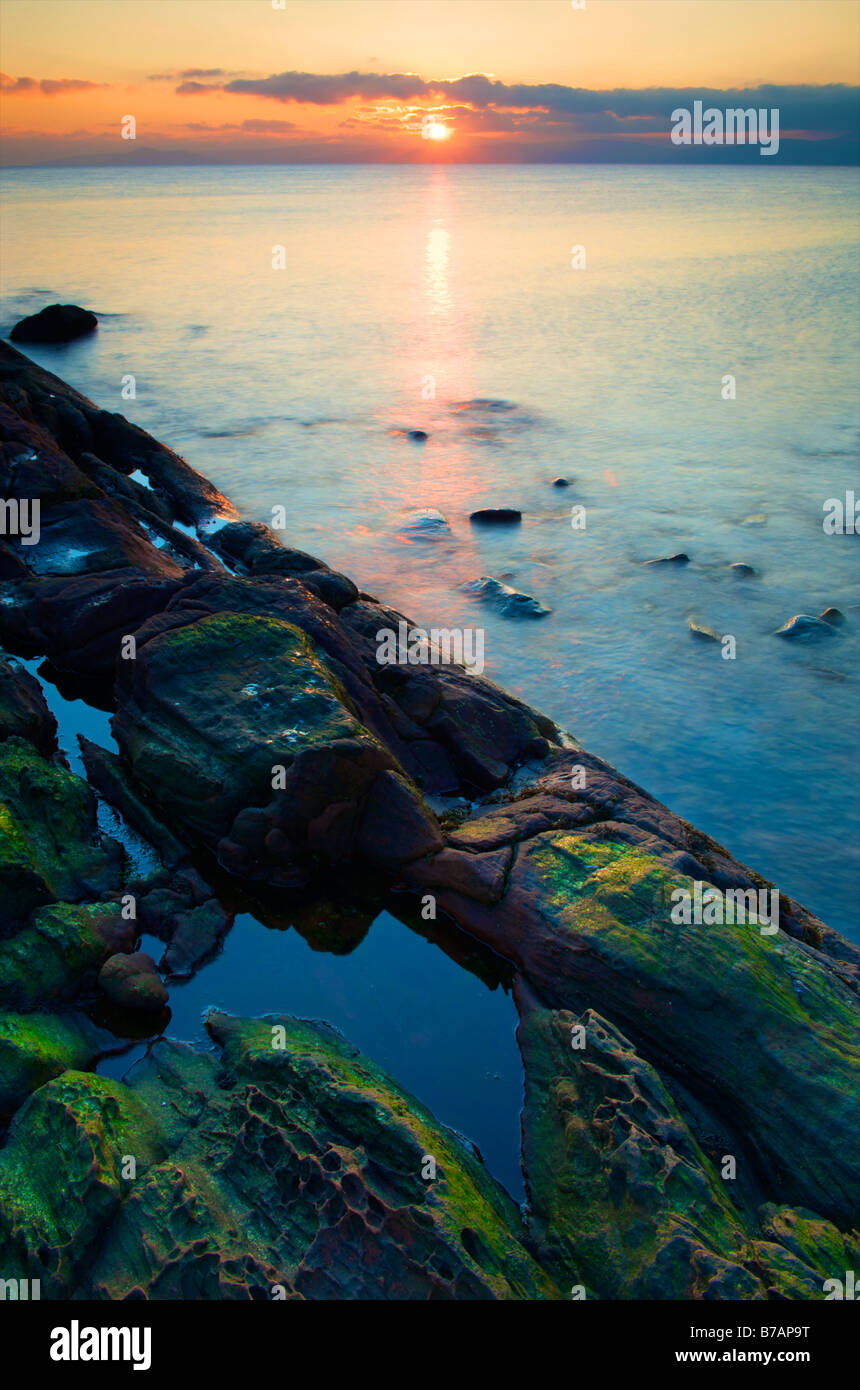seascape view of the river clyde at sunset over a rocky outcrop at low tide Stock Photo