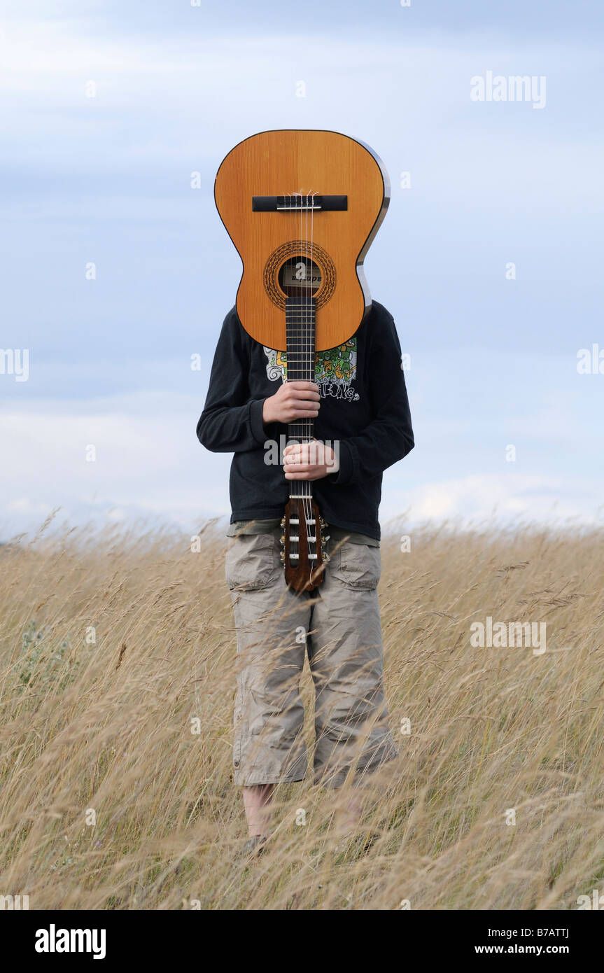 Boy Holding Guitar in Field Stock Photo