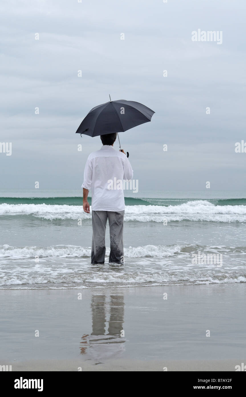 Man Holding Umbrella on Beach Stock Photo