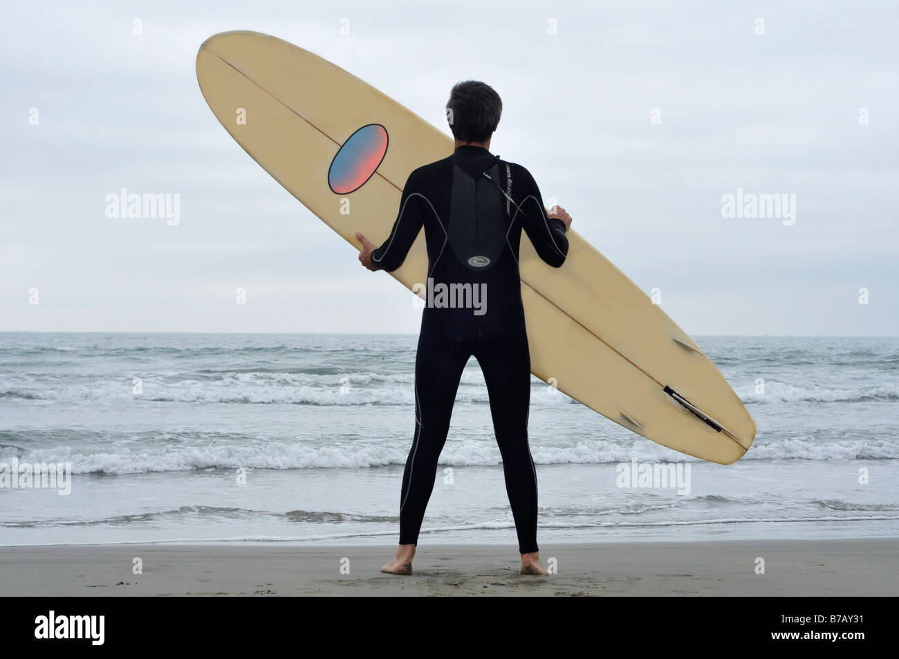 Man Holding Surfboard on Beach Stock Photo
