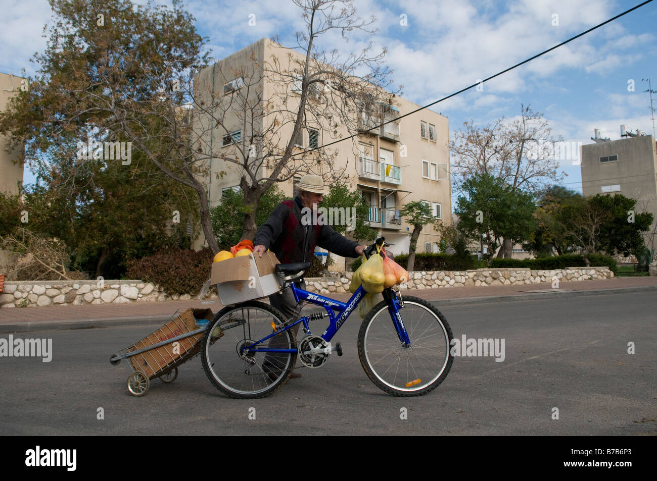 An elderly Israeli carrying food on his bicycle in a residential area in the southern town of Sderot, Israel Stock Photo