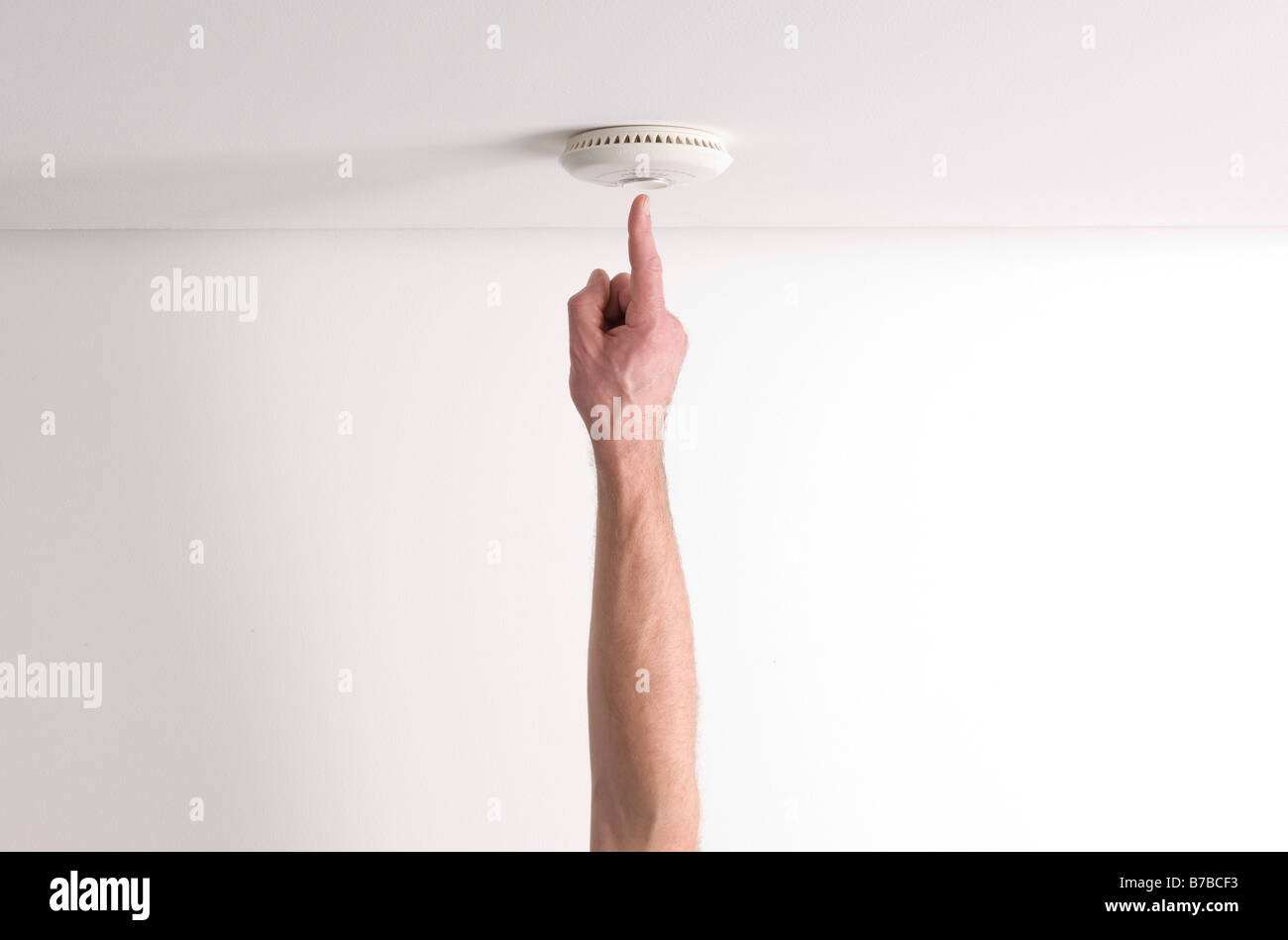 Man testing a domestic fire alarm is working correctly Stock Photo
