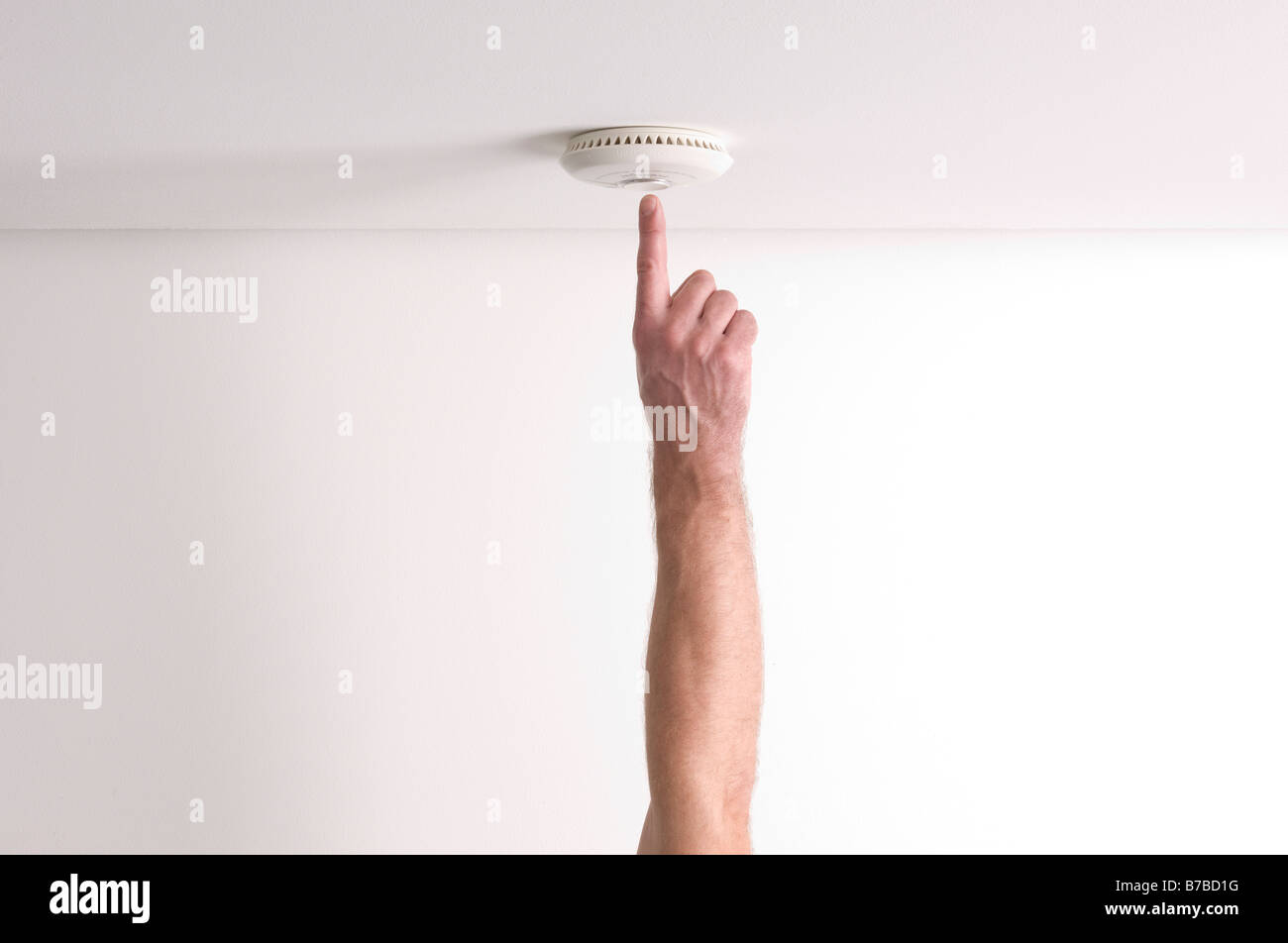 Man testing a domestic fire alarm is working correctly Stock Photo