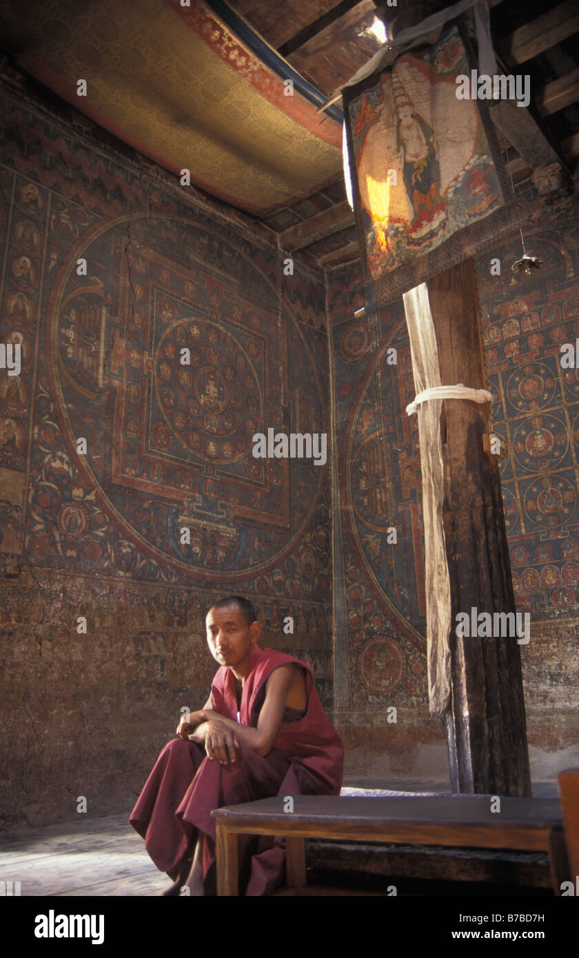 monk in khang prayer hall at Alchi gompa Indus valley Ladakh Jammu and Kashmir India. Ancient buddhist murals line the walls. Stock Photo