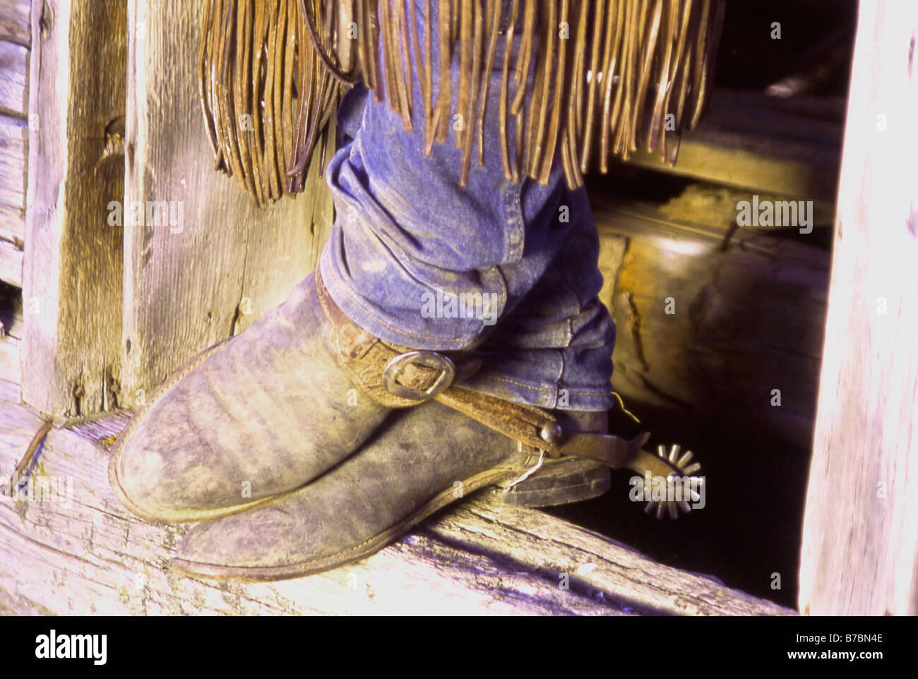 A cowboy s broken in trusty old boots in the doorway of an old log cabin on a ranch in Western United States Stock Photo