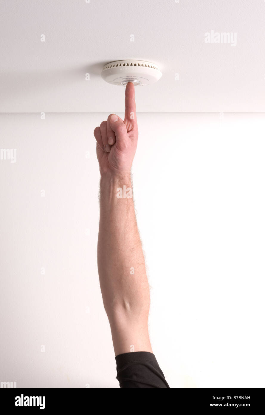 Man testing a domestic fire alarm is working correctly Stock Photo