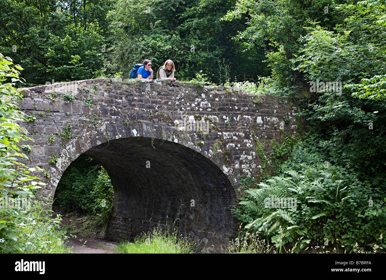 Two women walkers leaning over canal bridge Brecon and Monmouthshire canal Wales UK Stock Photo