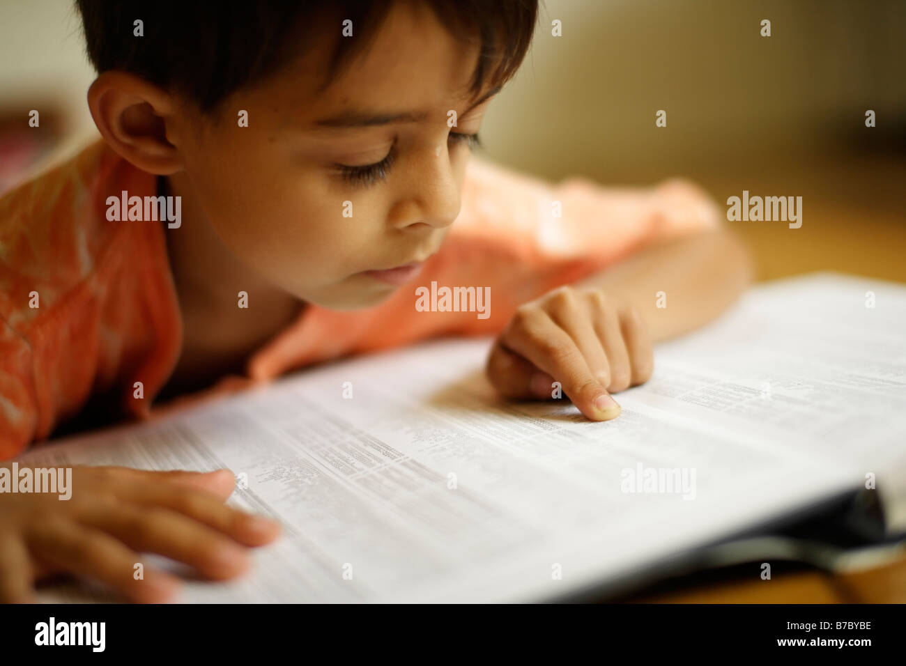 Six year old boy points to index of atlas Stock Photo