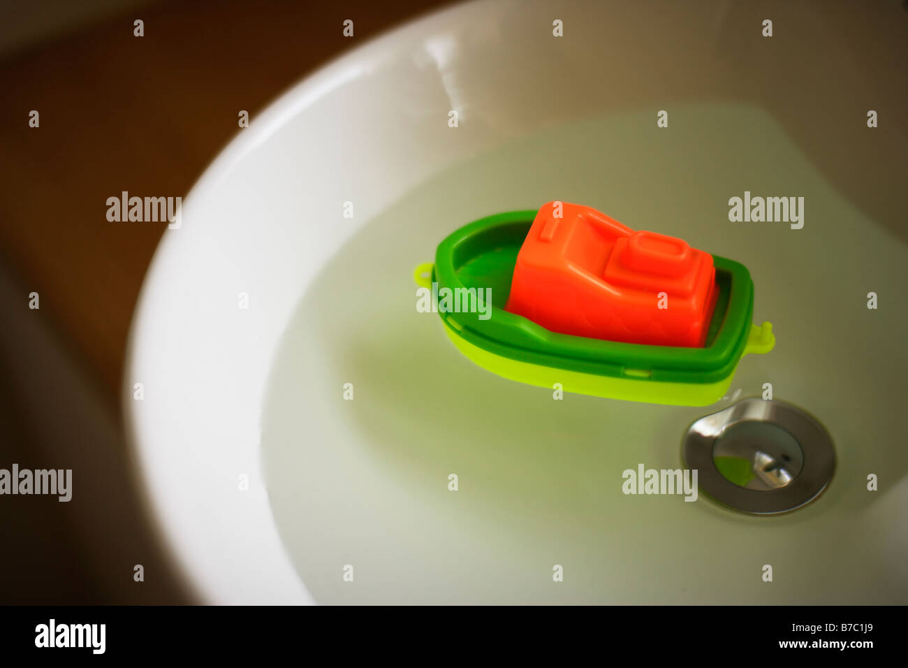 Child's toy plastic boat in sink full of water Stock Photo